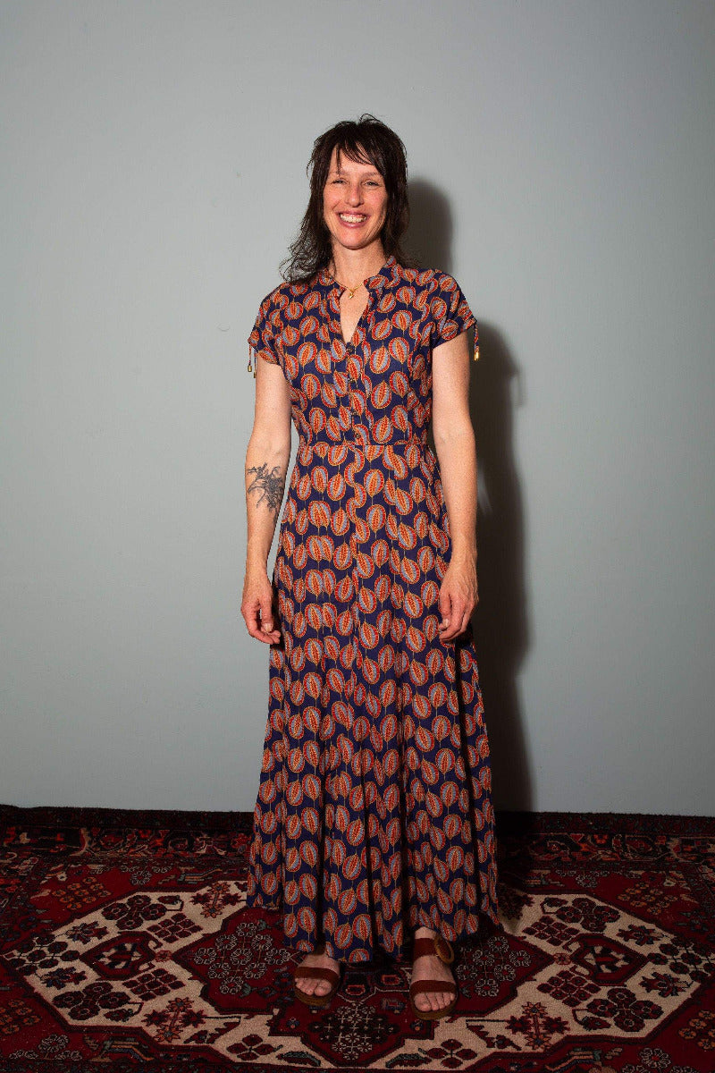 Woman wearing a patterned dress standing against a plain wall,  Sapling Textiles, Fabric Store Australia, Indian Fabric online Australia