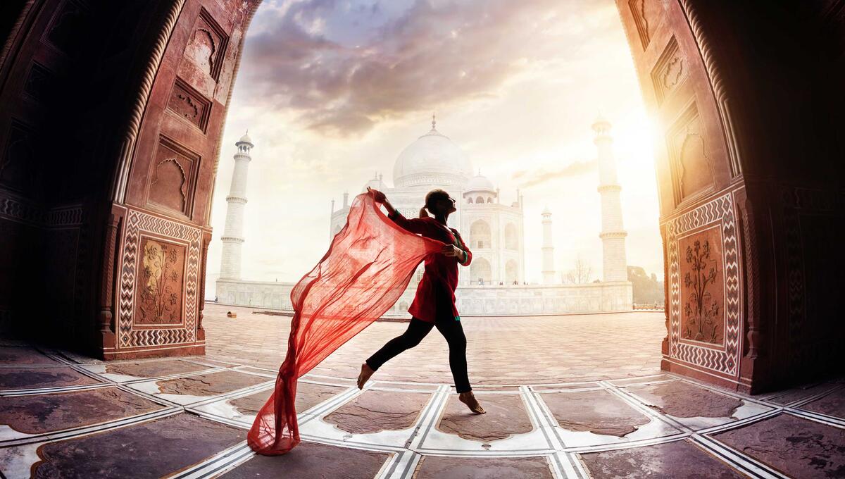 Person with a red fabric in front of a historic building at sunset, Sapling Textiles, Fabric Store Australia, Indian Fabric online Australia